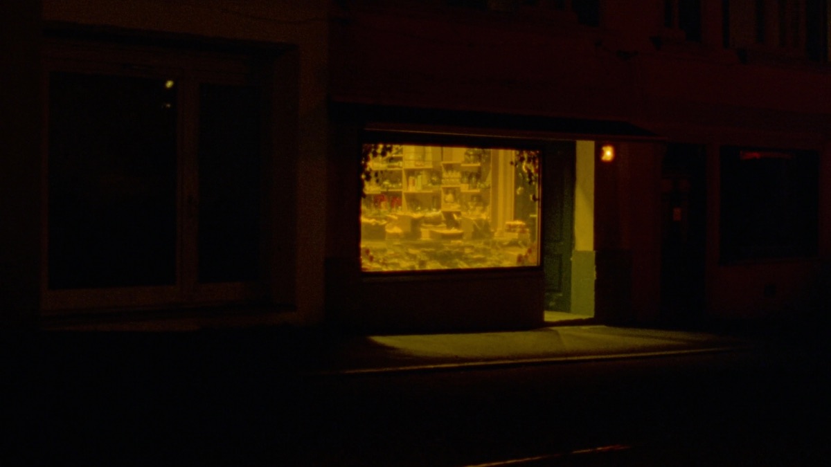 Warm erleuchtetes Schaufenster eines kleinen Ladenlokals bei Nacht, dessen Licht auf das dunkle Trottoir fällt — Sinnbild für ein lokales Geschäft, das gefunden wird.