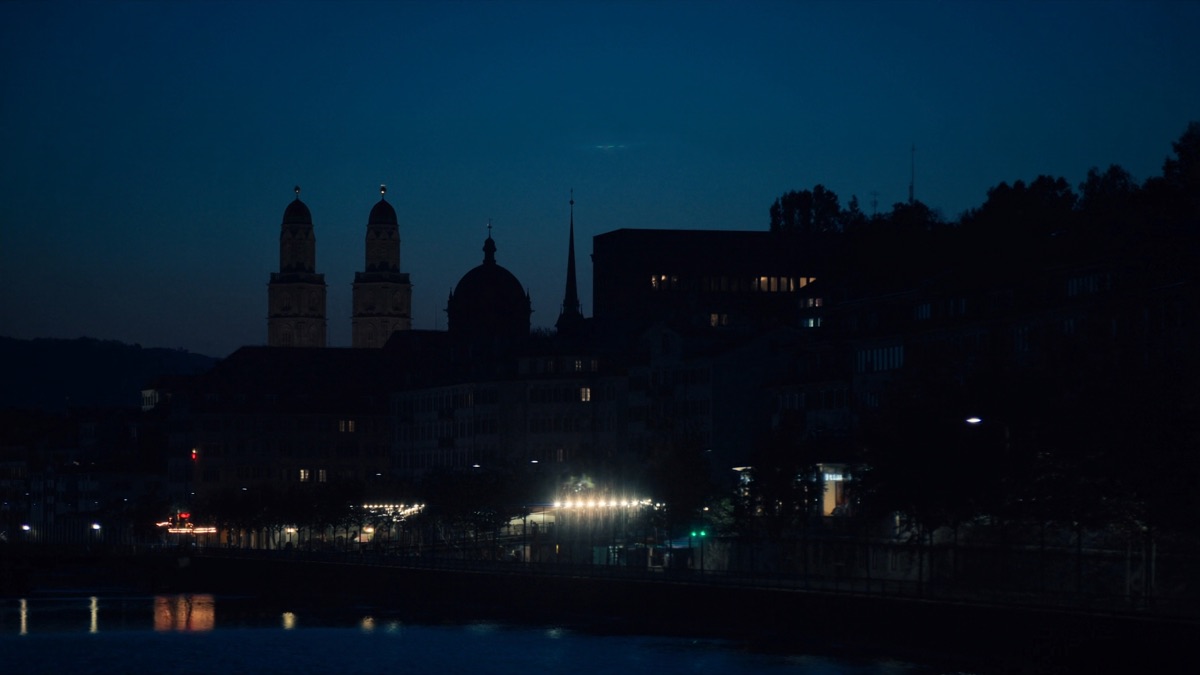 Zürich zur blauen Stunde: die Doppeltürme des Grossmünsters über der Limmat, die Lichter der Altstadt spiegeln sich im Wasser.